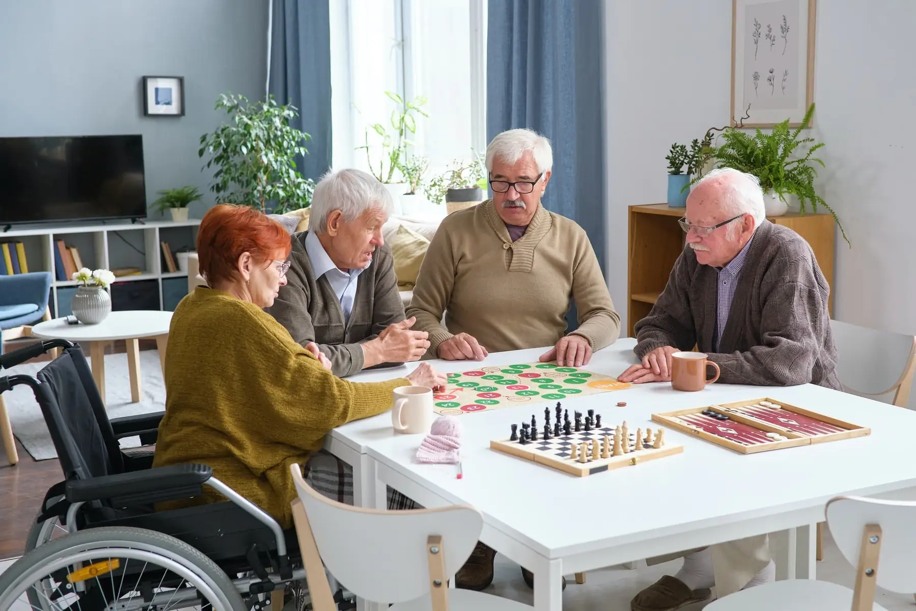 Des personnes aînées réunies autour d'une table de jeux de société dans une salle lumineuse.